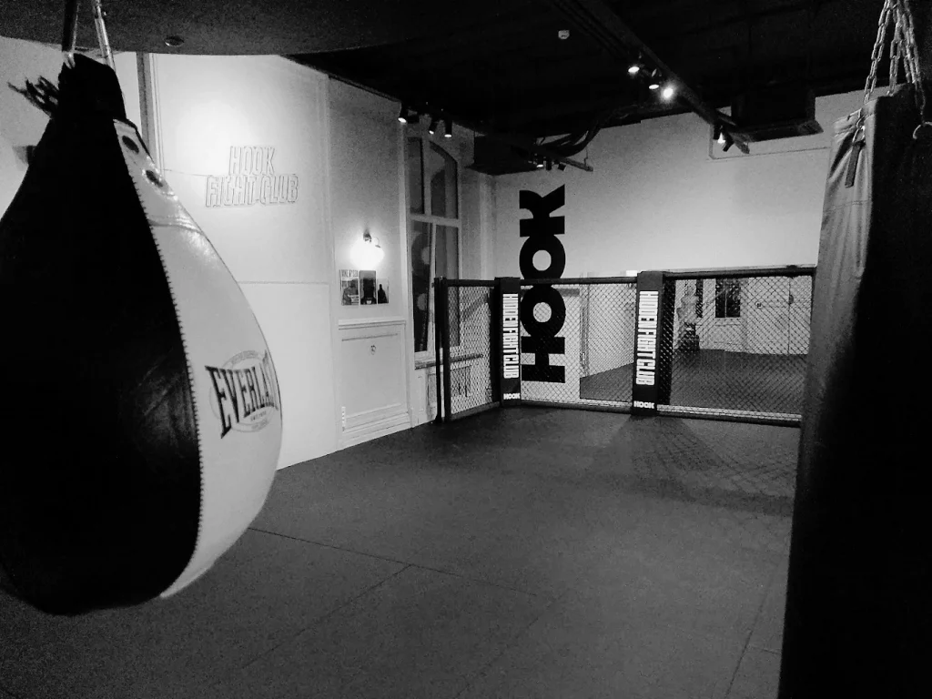 Le dojo de la salle de sport Le Hook a Lille : sacs de frappe et cage de MMA